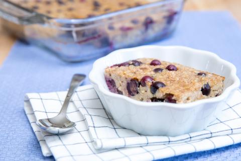 Baked blueberry banana oatmeal in a bowl, with a spoon.